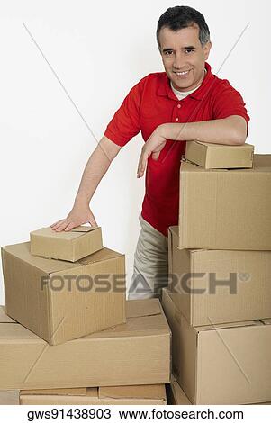 Portrait of a mid adult man standing with cardboard boxes View Large Photo Image Stock Image - Portrait of a mid adult man standing with cardboard boxes. Fotosearch