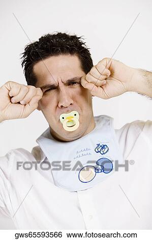 Stock Photograph - Portrait of a mid adult man sucking a pacifier and imitating a baby. Fotosearch