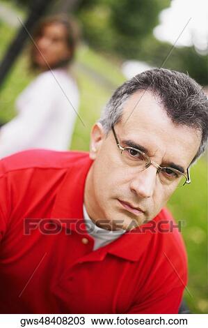 Portrait of a mid adult man with a mid adult woman sitting behind him View Large Photo Image Stock Image - Portrait of a mid adult man with a mid adult woman sitting behind him. Fotosearch