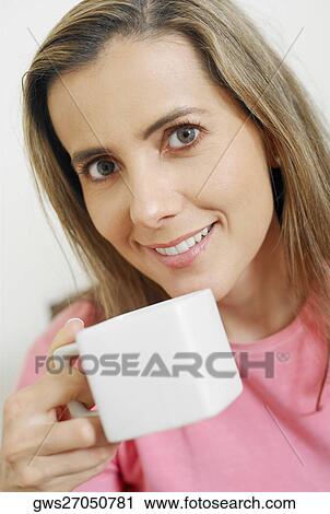 Portrait of a mid adult woman holding a cup of coffee View Large Photo Image Stock Image - Portrait of a mid adult woman holding a cup of coffee. Fotosearch