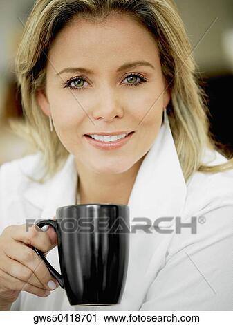 Portrait of a mid adult woman holding a cup and smiling View Large Photo Image Stock Image - Portrait of a mid adult woman holding a cup and smiling. Fotosearch