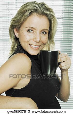 Portrait of a mid adult woman holding a cup of coffee View Large Photo Image Stock Image - Portrait of a mid adult woman holding a cup of coffee. Fotosearch