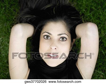Stock Photograph - Portrait of a mid adult woman lying on a lawn. Fotosearch