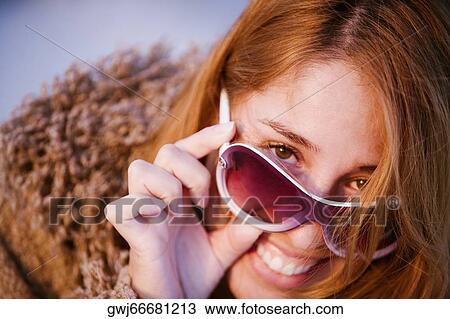 Stock Image - Portrait of a mid adult woman peeking over her sunglasses. Fotosearch
