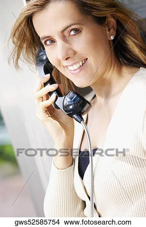 Portrait of a mid adult woman talking on a pay phone View Large Photo Image Picture - Portrait of a mid adult woman talking on a pay phone. Fotosearch