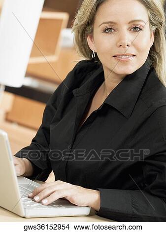 Portrait of a mid adult woman using a laptop View Large Photo Image Picture - Portrait of a mid adult woman using a laptop. Fotosearch