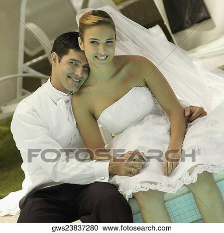 Portrait of a newlywed couple sitting at the poolside View Large Photo Image Stock Image - Portrait of a newlywed couple sitting at the poolside. Fotosearch