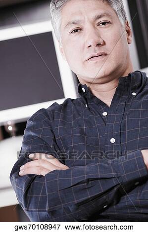 Stock Photo - Portrait of a senior man standing with his arms folded in front of a computer. Fotosearch