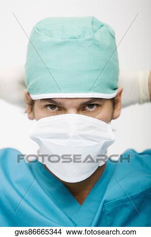 Portrait of a surgeon wearing a surgical mask on his face View Large Photo Image Picture - Portrait of a surgeon wearing a surgical mask on his face. Fotosearch