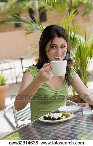 Stock Photograph - Portrait of a teenage girl drinking tea at a restaurant. Fotosearch