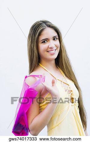 Stock Image - Portrait of a teenage girl holding a shopping bag and smiling. Fotosearch