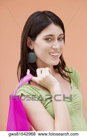 Stock Photo - Portrait of a teenage girl holding a shopping bag and smiling. Fotosearch
