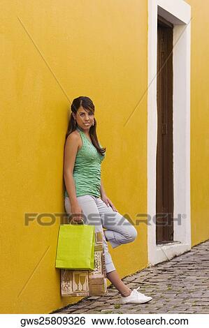 Portrait of a teenage girl leaning against the wall and holding shopping bags View Large Photo Image Stock Photograph - Portrait of a teenage girl leaning against the wall and holding shopping bags. Fotosearch