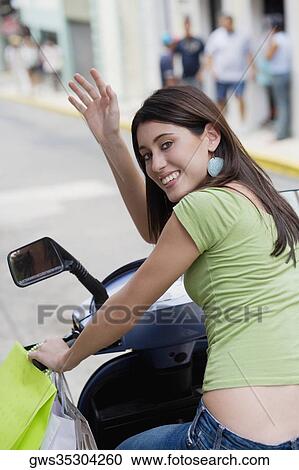 Portrait of a teenage girl riding on a scooter and waving her hand View Large Photo Image Stock Image - Portrait of a teenage girl riding on a scooter and waving her hand. Fotosearch