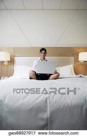 Portrait of a teenage girl sitting on the bed with a laptop View Large Photo Image Stock Photo - Portrait of a teenage girl sitting on the bed with a laptop. Fotosearch
