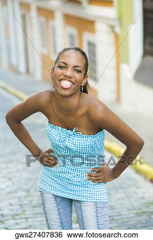 Portrait of a teenage girl sticking her tongue out with arms akimbo View Large Photo Image Stock Photograph - Portrait of a teenage girl sticking her tongue out with arms akimbo . Fotosearch