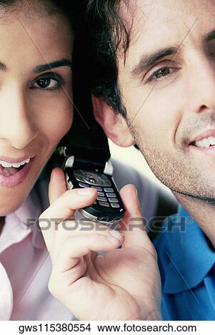 Portrait of a young couple using a mobile phone View Large Photo Image Picture - Portrait of a young couple using a mobile phone. Fotosearch