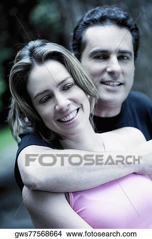 Portrait of a young man embracing a young woman from behind View Large Photo Image Picture - Portrait of a young man embracing a young woman from behind. Fotosearch