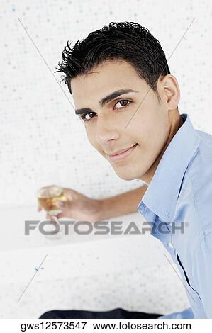 Portrait of a young man holding a glass of wine View Large Photo Image Stock Photo - Portrait of a young man holding a glass of wine. Fotosearch