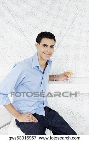 Stock Photo - Portrait of a young man holding a glass of wine and smiling. Fotosearch
