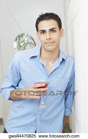 Stock Photography - Portrait of a young man holding a glass of martini. Fotosearch