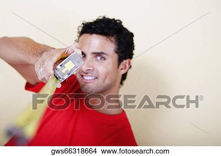 Portrait of a young man holding a measuring tape and smiling View Large Photo Image Picture - Portrait of a young man holding a measuring tape and smiling. Fotosearch