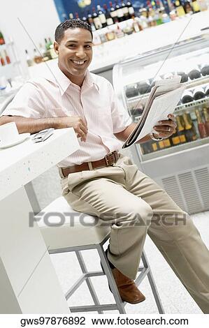 Portrait of a young man holding a newspaper and smiling View Large Photo Image Stock Image - Portrait of a young man holding a newspaper and smiling. Fotosearch