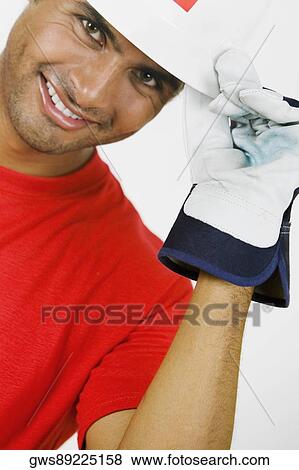 Stock Photo - Portrait of a young man holding a hardhat and smiling. Fotosearch