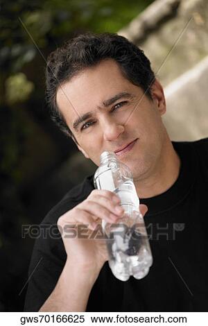 Stock Photography - Portrait of a young man holding a water bottle. Fotosearch