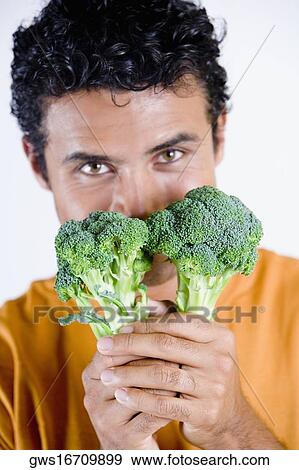 Portrait of a young man holding broccoli in front of his face View Large Photo Image Stock Photo - Portrait of a young man holding broccoli in front of his face. Fotosearch