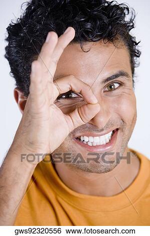 Portrait of a young man looking through a circle formed by his fingers View Large Photo Image Stock Photograph - Portrait of a young man looking through a circle formed by his fingers. Fotosearch