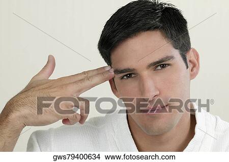 Portrait of a young man making a gun sign close to his temple View Large Photo Image Picture - Portrait of a young man making a gun sign close to his temple. Fotosearch