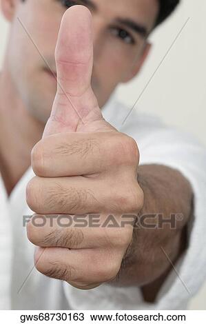 Portrait of a young man showing a thumbs up sign View Large Photo Image Stock Image - Portrait of a young man showing a thumbs up sign. Fotosearch