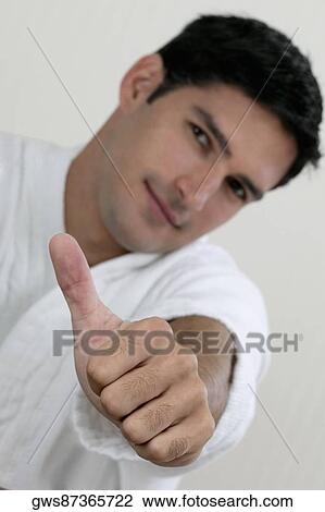 Portrait of a young man showing a thumbs up sign View Large Photo Image Stock Image - Portrait of a young man showing a thumbs up sign. Fotosearch