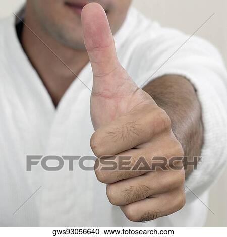 Stock Image - Portrait of a young man showing a thumbs up sign. Fotosearch