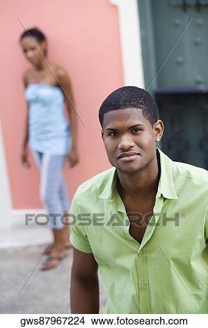 Portrait of a young man standing with a teenage girl behind him View Large Photo Image Picture - Portrait of a young man standing with a teenage girl behind him. Fotosearch
