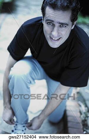 Portrait of a young man tying his shoe laces View Large Photo Image Picture - Portrait of a young man tying his shoe laces. Fotosearch