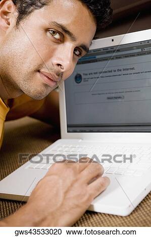 Stock Image - Portrait of a young man using a laptop. Fotosearch