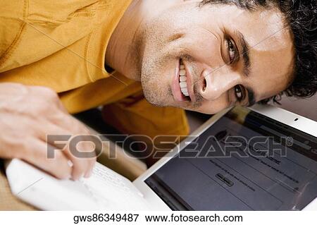 Portrait of a young man using a laptop View Large Photo Image Stock Photo - Portrait of a young man using a laptop. Fotosearch