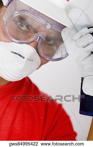 Stock Image - Portrait of a young man wearing a hardhat with a pollution mask and a protective eyewear. Fotosearch