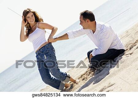 Portrait of a young woman and a mid adult man romancing on the beach View Large Photo Image Picture - Portrait of a young woman and a mid adult man romancing on the beach. Fotosearch