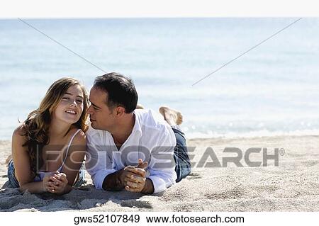 Portrait of a young woman and a mid adult man lying on the beach View Large Photo Image Stock Photo - Portrait of a young woman and a mid adult man lying on the beach. Fotosearch