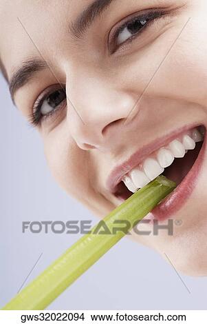 Portrait of a young woman biting into a celery stick View Large Photo Image Picture - Portrait of a young woman biting into a celery stick. Fotosearch