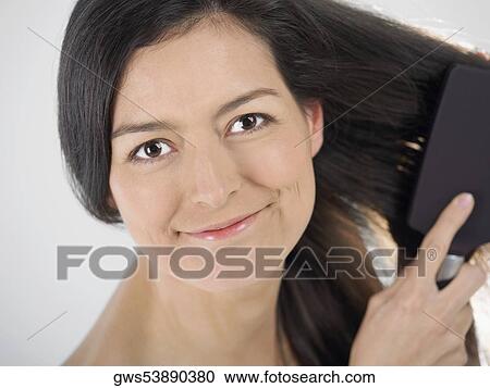 Portrait of a young woman brushing her hair View Large Photo Image Stock Image - Portrait of a young woman brushing her hair. Fotosearch