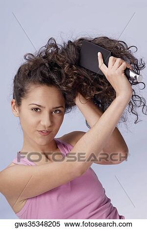 Portrait of a young woman brushing her hair View Large Photo Image Stock Photography - Portrait of a young woman brushing her hair. Fotosearch