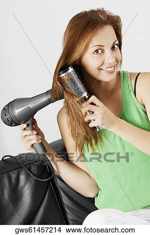 Picture - Portrait of a young woman drying her hair with a hair dryer. Fotosearch