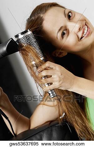 Stock Photography - Portrait of a young woman drying her hair with a hair dryer. Fotosearch