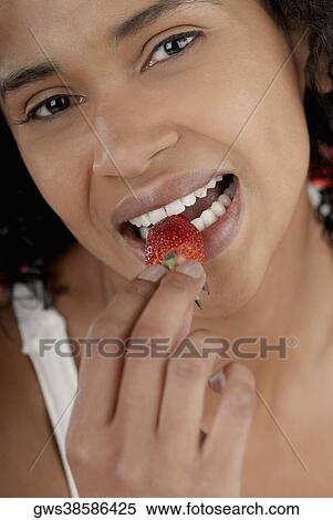 Portrait of a young woman eating a strawberry View Large Photo Image Stock Photography - Portrait of a young woman eating a strawberry. Fotosearch