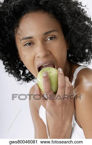 Stock Image - Portrait of a young woman eating an apple. Fotosearch