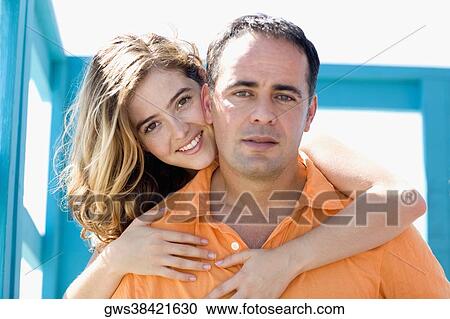 Portrait of a young woman embracing a mid adult man from behind View Large Photo Image Stock Image - Portrait of a young woman embracing a mid adult man from behind. Fotosearch